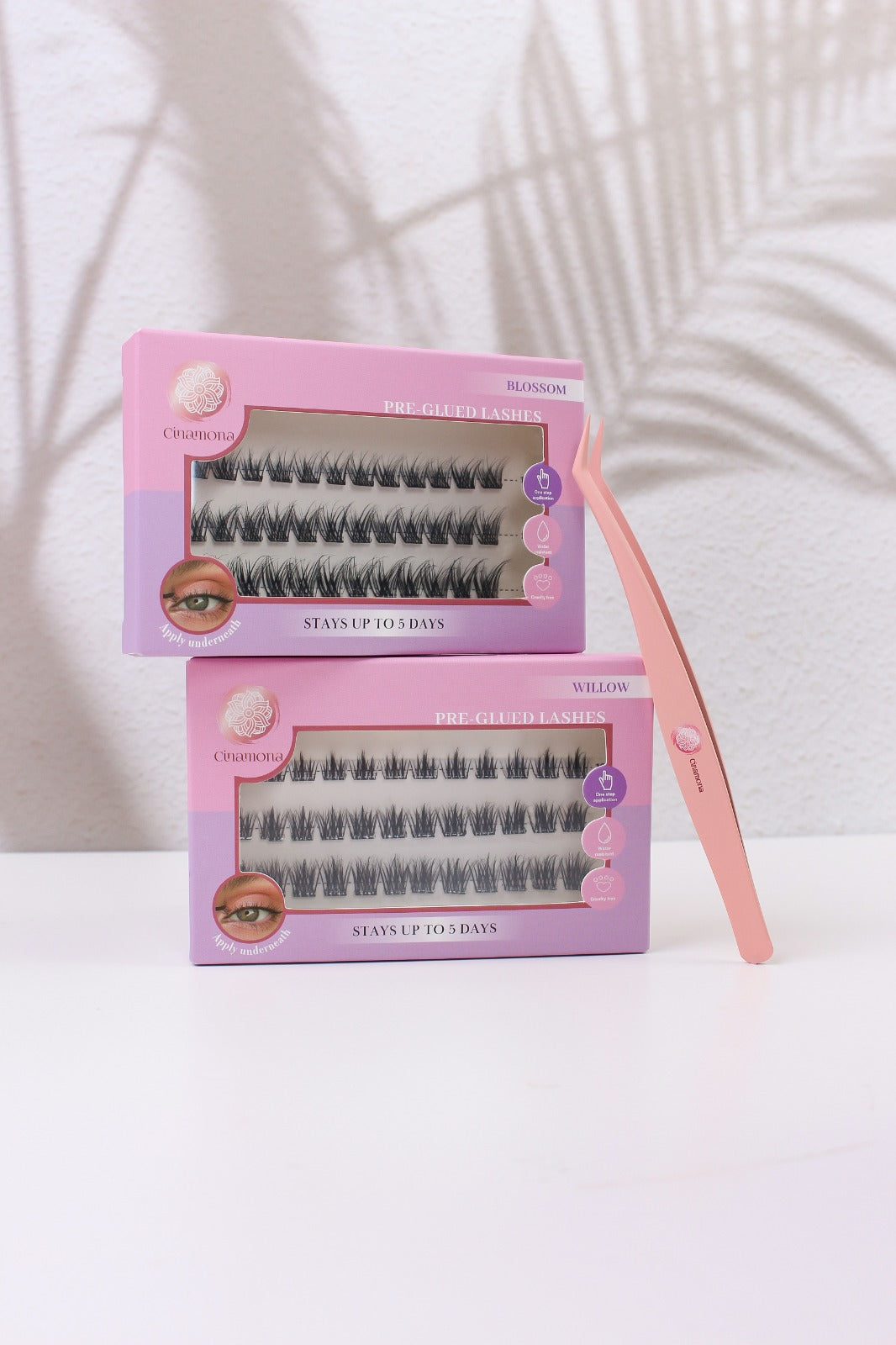 False eyelashes in pink packaging with a pink tweezers on a white background